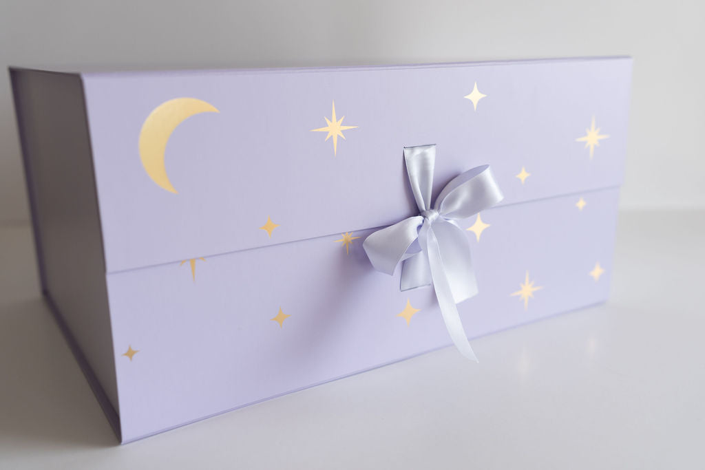 Purple gift box with star and moon designs and a silver bow on a light gray background
