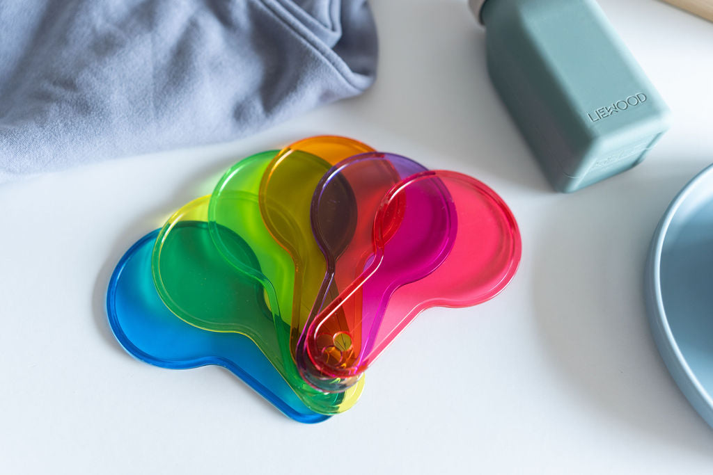 Set of colorful gel pads on a white surface with a bottle in the background.